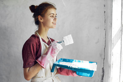 Portrait of young woman standing against wall