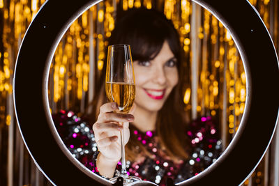Portrait of smiling young woman with champagne against decorations