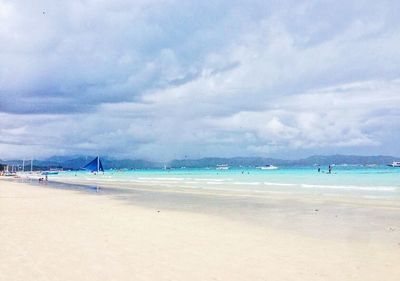 Scenic view of beach against cloudy sky