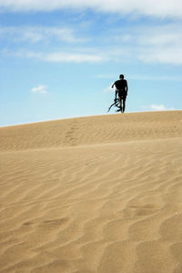 Teenage boy in costume on desert against sky