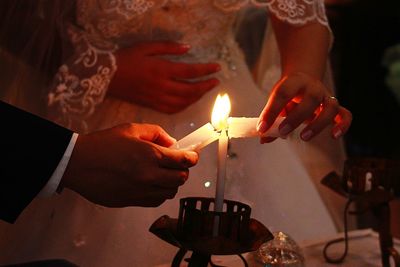 Midsection of woman holding burning candles