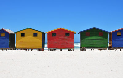 Lounge chairs on beach against clear blue sky