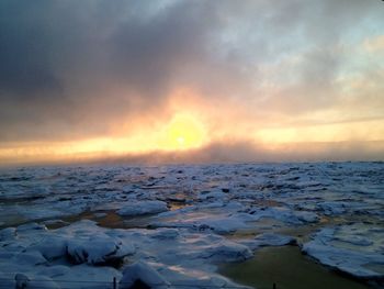 Scenic view of sea against cloudy sky during sunset