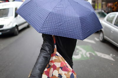 Woman with umbrella walking on road