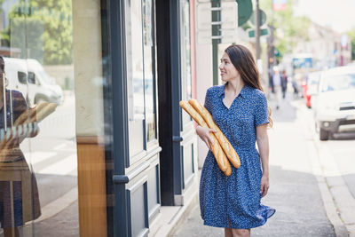 Young woman buying a french baguette