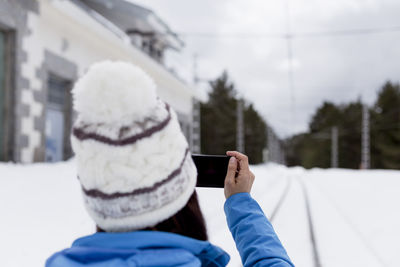 Rear view of man using mobile phone in snow