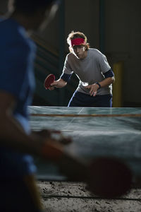 Young friends playing table tennis at night