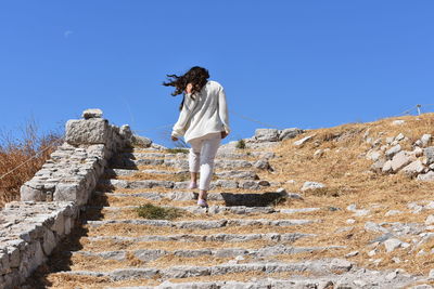 Woman standing on staircase against clear sky