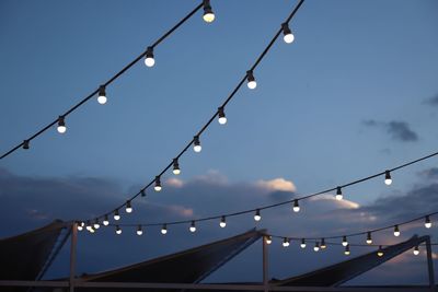 Low angle view of illuminated lights against sky at dusk