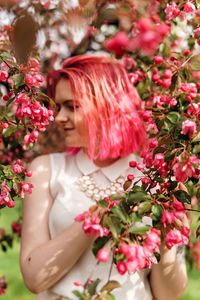 Young girl with pink hair in apple orchard.