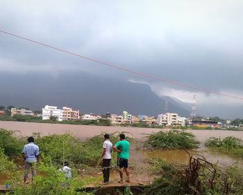 Rear view of men with umbrella against sky