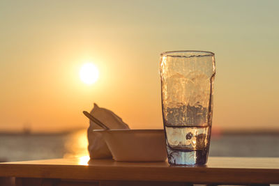 Wine glass on table against sea during sunset