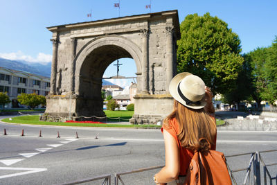 Tourism in italy. back view of tourist girl looking the arch of augustus in aosta, italy.