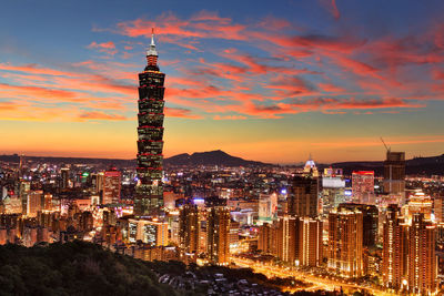 Illuminated cityscape against sky during sunset