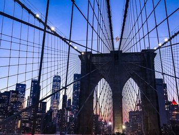 Low angle view of suspension bridge in city against sky