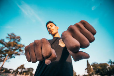 Low angle view of young man against blue sky