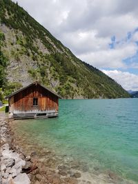 Log cabin by sea against mountain