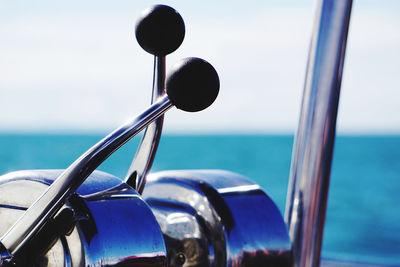 Close-up of metallic structure in sea against sky