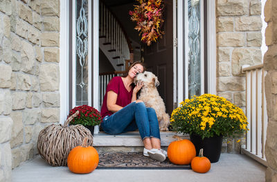 Rear view of woman with dog sitting by flowers