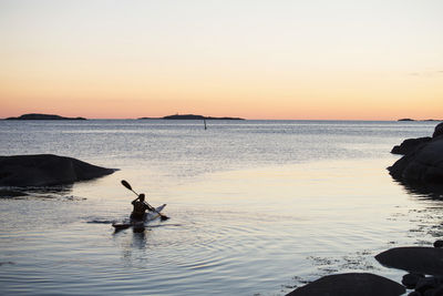 Rear view of man kayaking in river at dusk