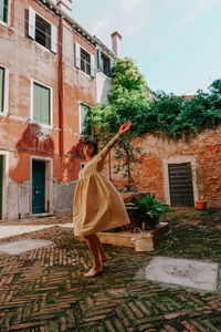 Woman standing by tree outside house