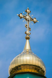 Low angle view of weather vane against blue sky