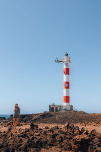 People at beach against clear blue sky