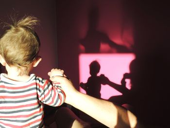 Cropped hand holding baby while standing at home