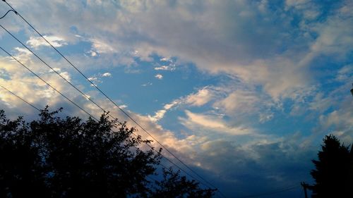 Low angle view of silhouette trees against cloudy sky