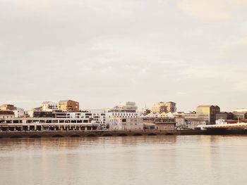 River by buildings in city against sky