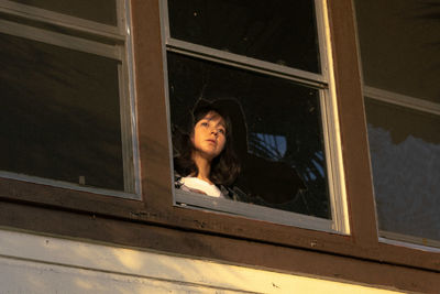 Portrait of woman looking through window