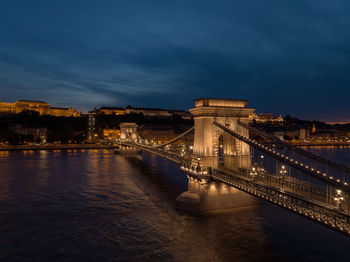 Illuminated bridge over river against sky at night