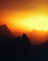 Scenic view of silhouette mountains against orange sky