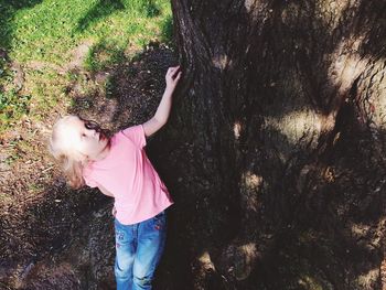 Girl standing by tree during sunny day