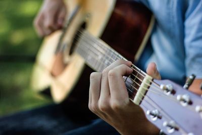 Midsection of man playing guitar