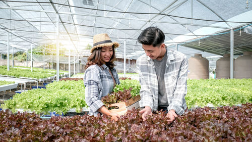 Happy young woman standing in greenhouse