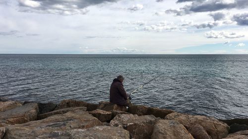 Rear view of man fishing at sea shore