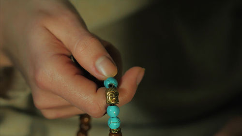 Cropped hand of person holding bead necklace