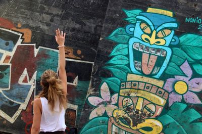 Rear view of woman standing against graffiti wall