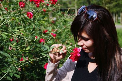 Beautiful woman smelling flower in park