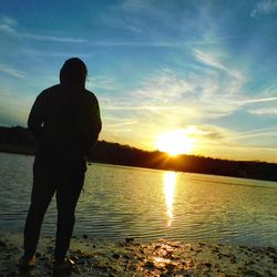 Silhouette man looking at sea against sky during sunset