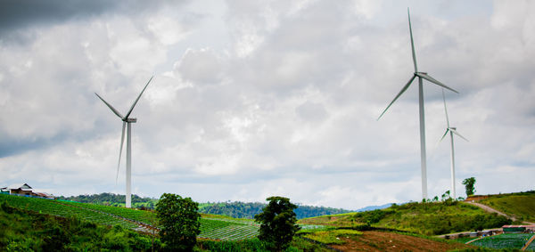 Wind turbines on field against sky