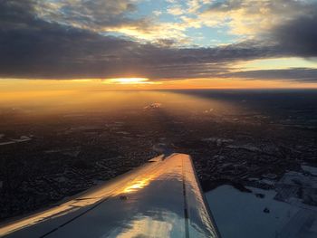 Cropped image of airplane wing over landscape during sunset