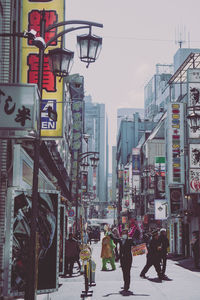 People walking on road against buildings in city