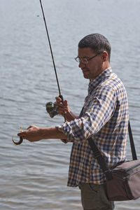 Man holding fishing rod by water