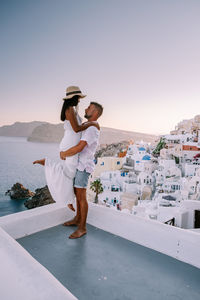 Rear view of couple standing by sea against clear sky