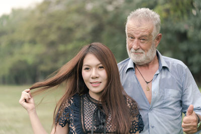 Portrait of father gesturing thumbs up while standing with daughter at park