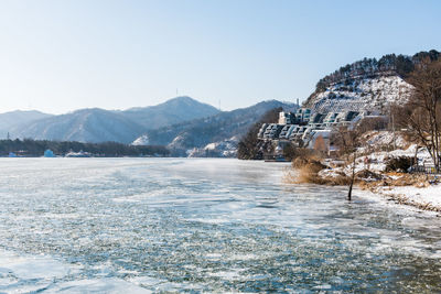 Scenic view of lake by mountain against sky during winter