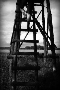 Low angle view of man standing on railing against sky