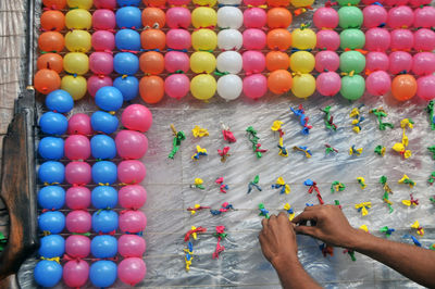 Cropped hand removing damaged balloons on string at arcade game